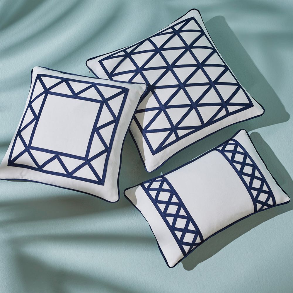 A stylish cushion by Jonathan Adler with a pattern formed from navy, raised ribbon embroidery on a ivory cover