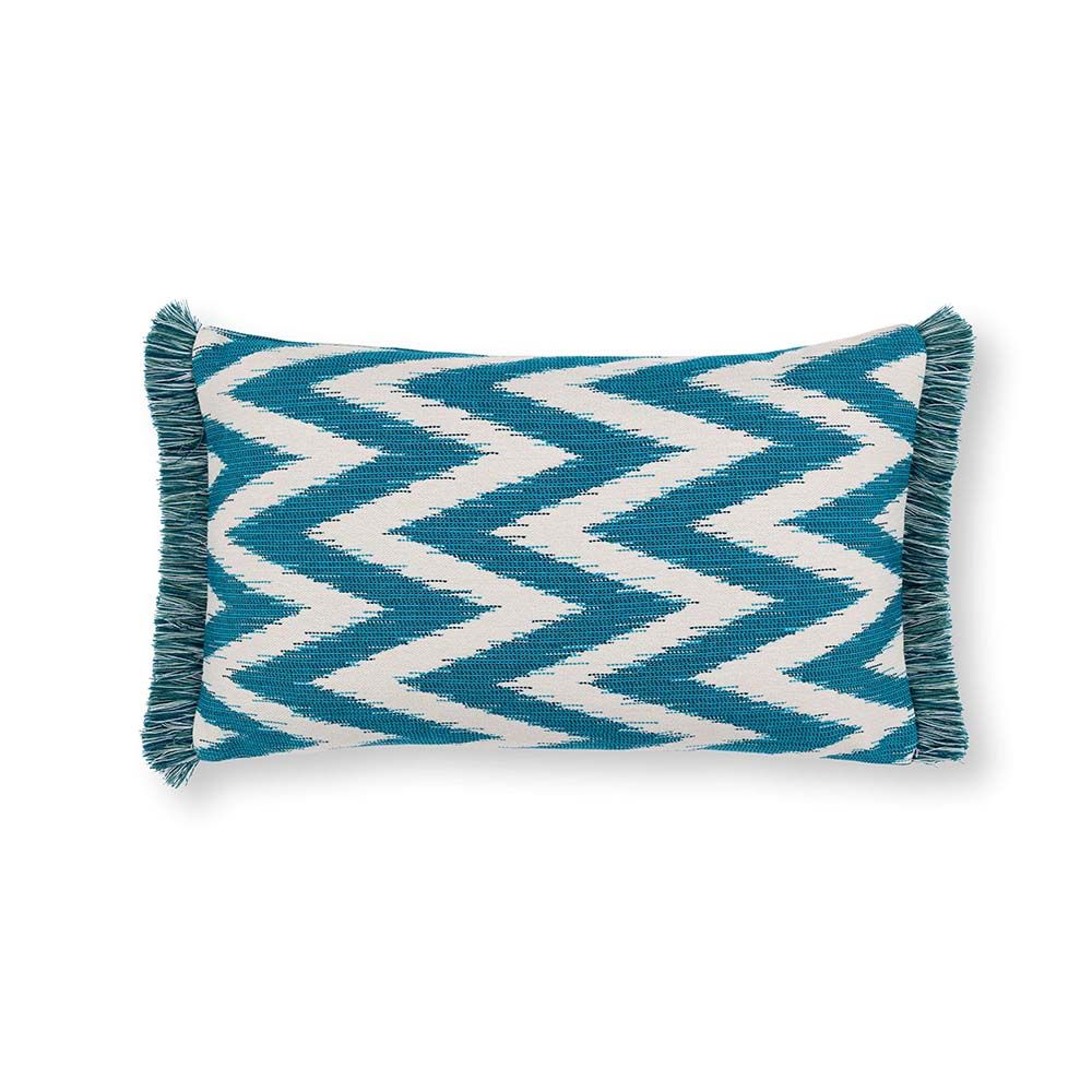 A teal, zigzag patterned cushion with matching fringe details.