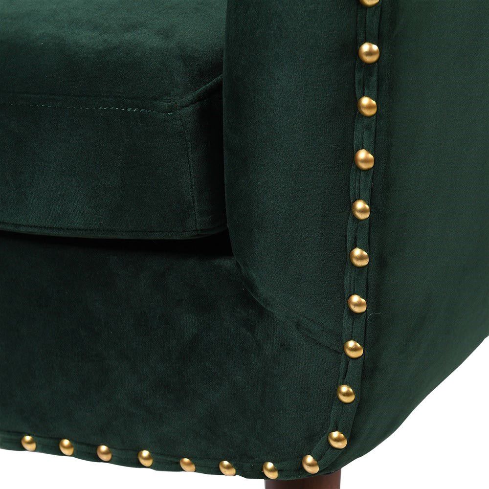 A luxurious green velvet armchair with brass studs and brown legs with brass caps