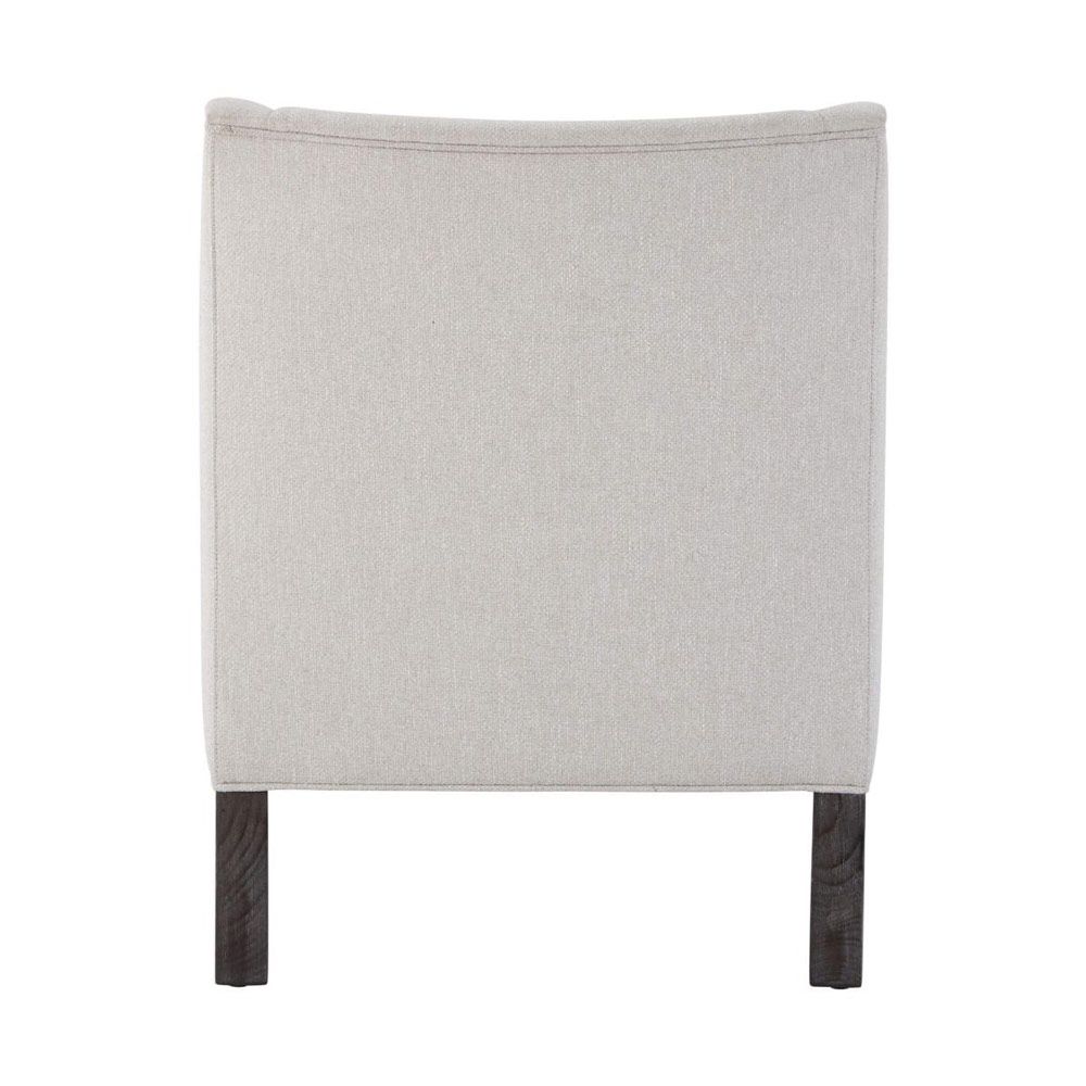 A stylish armchair with a grey upholstery, chic curves and wavy armrests 