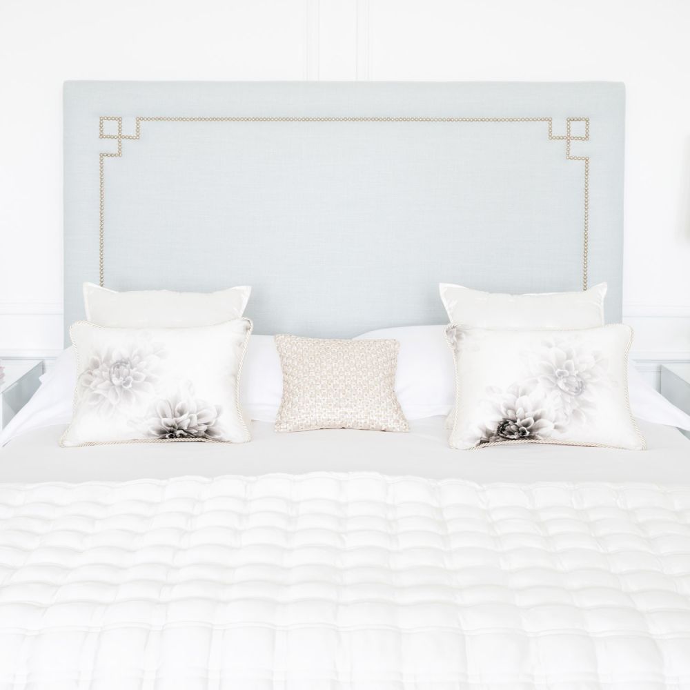 Luxury blue grey linen bed with an elegant tall headboard, with an art deco studding design