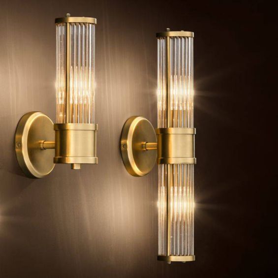 A glamorous wall lamp with an antiqued brass finish and reeded glass