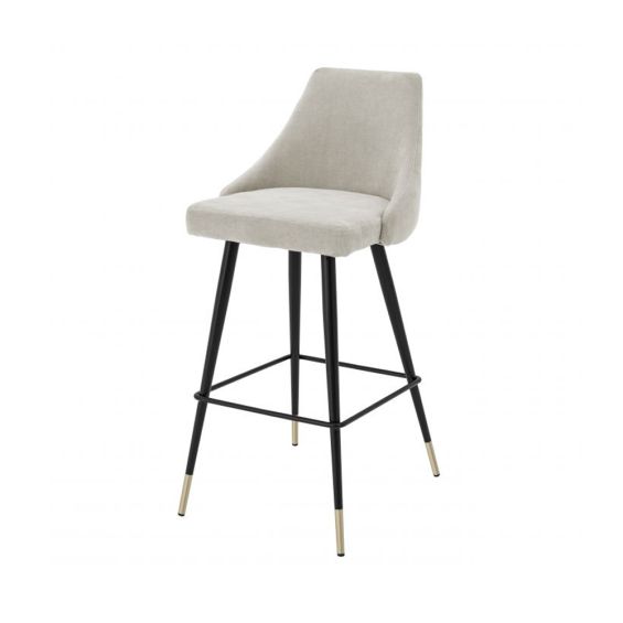 A luxurious bar stool in a sand-toned fabric with polished brass detailing