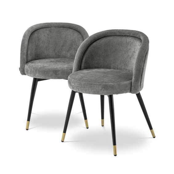 A luxurious set of two velvet dining chairs with black tapered legs and golden caps