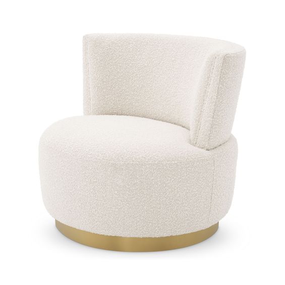 A beautiful armchair with boucle upholstery and a brushed brass swivel base