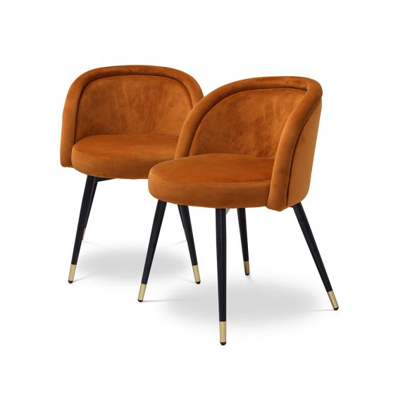 A luxury set of dining chairs with an orange velvet upholstery and golden capped feet