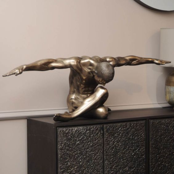 Brass toned sculpture of man with outstretched arms