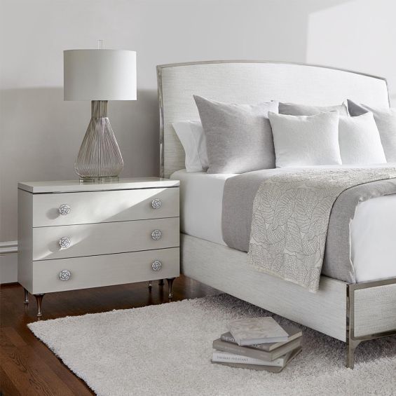 A luxurious, eggshell bedside table with three drawers.