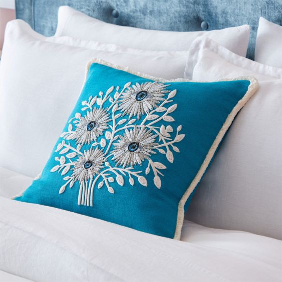 Ornate tree of eyes illustration blue cushion with white fringe. 