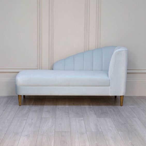 A curvaceous chaise longue with a pale blue velvet upholstery and seashell-like frame 