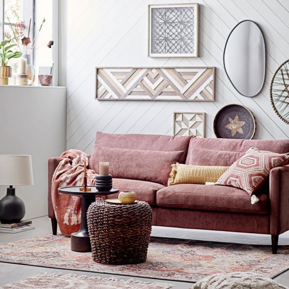 A warm cushion with an intricate embroidered pattern on warm brown linen with added tufted tassel details on each corner