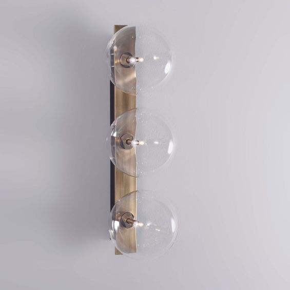 A glamorous industrial-style triple light wall lamp in a lacquered burnished brass finish