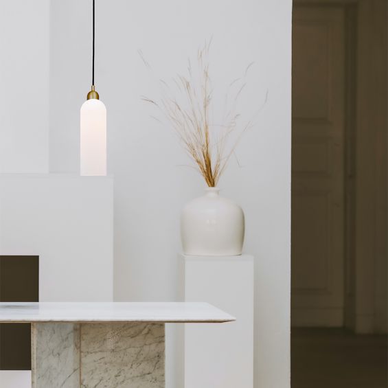 A luxury single pendant by Schwung with a natural brass finish and frosted glass shade