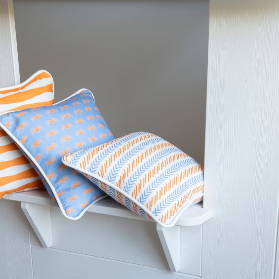 A colourful children's cushion with an orange and blue pattern and finished with white piping