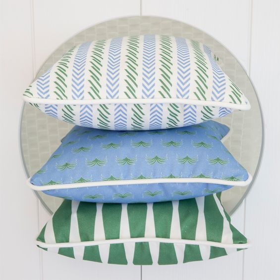 A statement children's cushion featuring a bold green and blue pattern with white piping