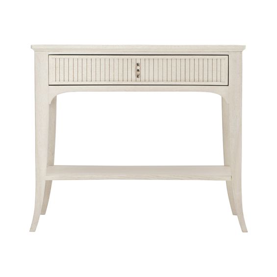A sophisticated one-drawer bedside table with a concave shape, quartered white oak veneers, a Manor White finish and silver luster highlights