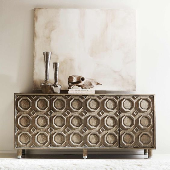 A textured wooden sideboard with four carved geometric patterned doors and finished with nickel plated aluminium legs