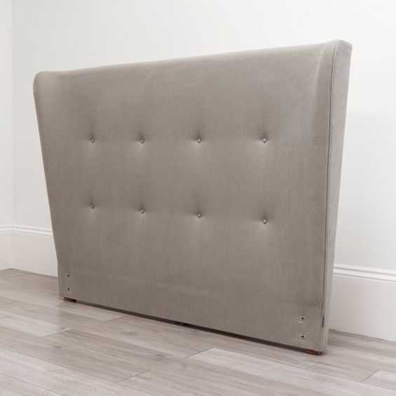 A beige linen upholstered headboard with shallow buttoning
