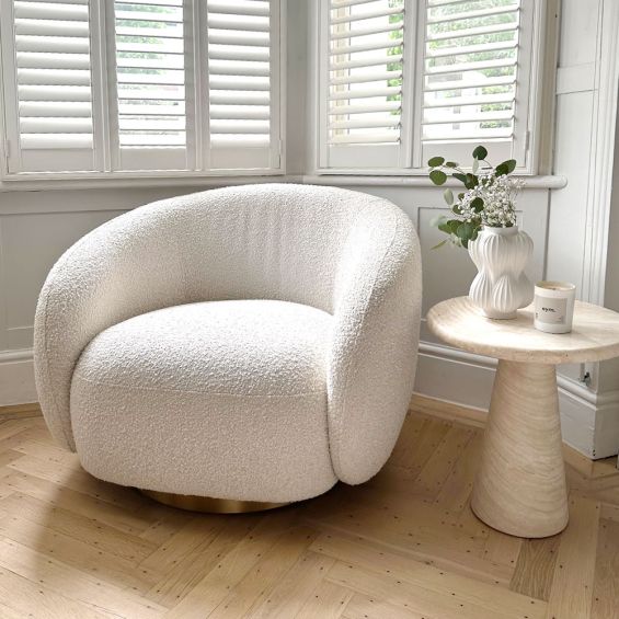 A sumptuous art deco inspired armchair with a brushed brass swivel base