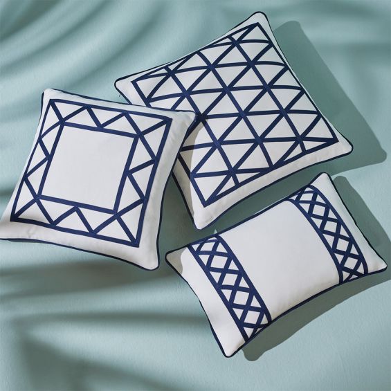 A chic cushion by Jonathan Adler with an ivory cover and navy raised ribbon embroidery