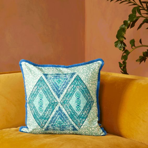 A vibrant cushion by Eva Sonaike with a turquoise African-inspired pattern and fringing