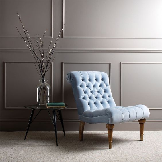 A luxury occasional chair with a blue, silky upholstery and buttoned back