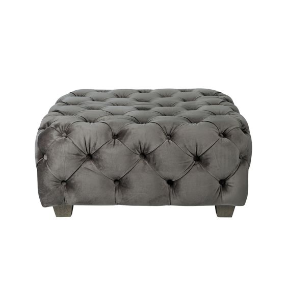 A luxurious dark grey velvet pouffe with deep buttoning