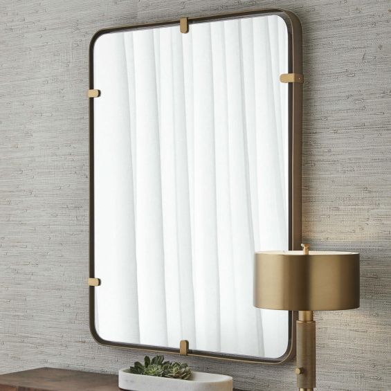 Bronze-finished structure surrounding wall mirror held by clips in a brass finish