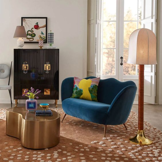 A stylish sofa by Jonathan Adler with a luxury blue upholstery and brass legs