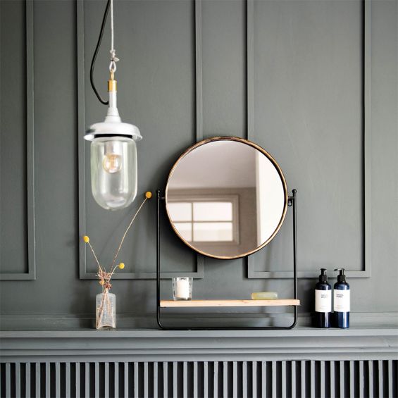 A classic round table mirror with a bronze finish and wooden shelf