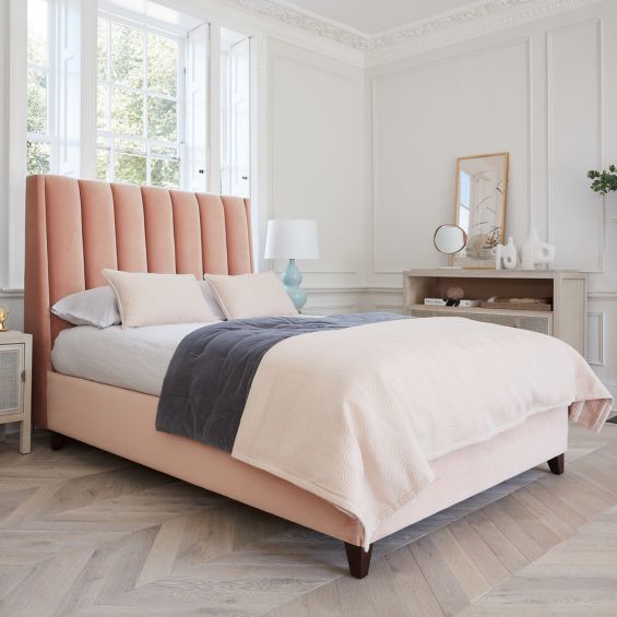 A luxurious Handmade in London bed with velvet upholstery, a fluted headboard and wooden legs