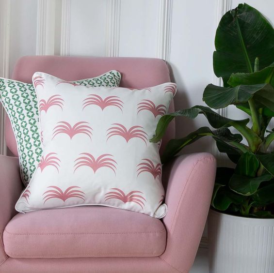 A stunning white cushion with matching piping and a delicate pink leaf-like pattern