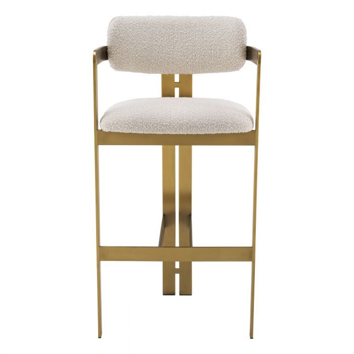 A luxury bar stool by Eichholtz with a boucle seat and brushed brass legs