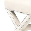 A delicate white velvet footstool adorned with nickel studs.