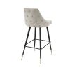 A luxurious bar stool in a sand-toned fabric with polished brass detailing