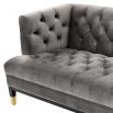 grey deep-buttoned sofa with velvet upholstery and black legs with gold accents