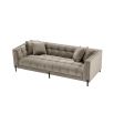 A luxurious sumptuous deep-buttoned sofa with grey velvet upholstery and black legs 