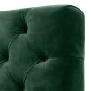 green velvet upholstered deep-buttoned sofa with black legs and brass accents 