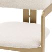 A chic and contemporary brushed brass dining chair upholstered in boucle fabric 