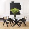 An iconic, black Jeanneret-inspired dining chair with a rattan seat and backrest