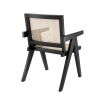 An iconic, black Jeanneret-inspired dining chair with a rattan seat and backrest
