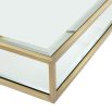 A contemporary glass coffee table with a brushed brass finish