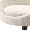 A glamorous dining chair by Eichholtz with a luxurious boucle cream upholstery, tub-shaped seat and black swivel base
