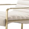 A luxurious boucle upholstered armchair with a brushed brass base