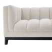 A cosy and luxurious boucle cream sofa with a contrasting black finish base by Eichholtz 