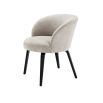 A stylish dining chair by Eichholtz with a beige upholstery, curved back and black tapered legs