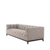 A gorgeous rustic inspired sofa upholstered in a beige fabric with black features.