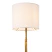 A luxurious floor lamp by Eichholtz with an antique brass base finished with a circular white marble plinth and off-white shade