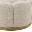 A stunning floral inspired ottoman with a curvilinear shape, a glamorous brushed brass swivel base and a luxurious boucle cream upholstery with deep channel stitching