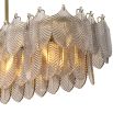 A beautiful chandelier by Eichholtz with a rectangular shape, brushed brass finish and smoke glass decorative leaf details
